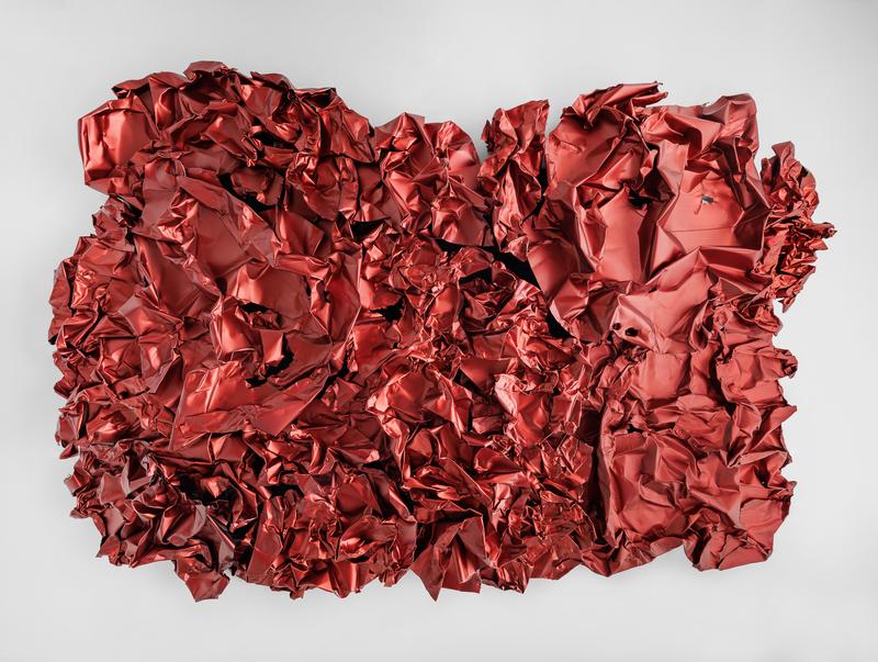 Dieses Kunstwerk ist von Hans Kupelwieser.
Es ist ein großes rotes Wandrelief aus Aluminium.
Das Material wurde zerknittert und geformt,
sodass es aussieht wie zerdrücktes Geschenkpapier oder eine riesige rote Folie.

Die Oberfläche ist nicht glatt, sondern faltig und voller Dellen und Löcher.
Das sieht aus, als wäre es zufällig entstanden, aber es ist genau geplant.
Kupelwieser benutzt dafür Maschinen und Greifbagger, die das Aluminium verformen.

Die rote Farbe kommt von einem chemischen Verfahren, das man Eloxieren nennt.
Dadurch sieht das Metall matt und weich aus – obwohl es eigentlich hart ist.

Das Kunstwerk hängt an der Decke des Tea Rooms im Museum der Heidi Horten Collection in Wien.

Kupelwieser spielt hier mit Gegensätzen:
leicht und schwer, weich und hart, Zufall und Planung.