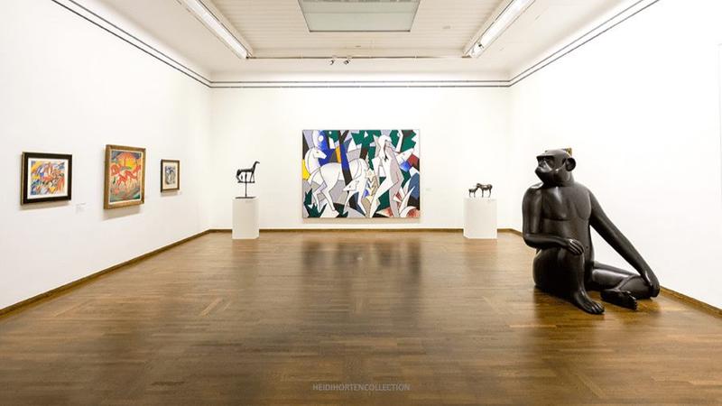 Moderne Kunstwerke und Skulpturen in einer hellen Galerie mit Holzfußboden.