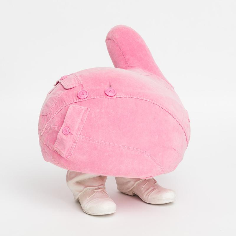 Runde, pinke Skulptur mit Knöpfen und einem Schuhpaar, das auf einem weißen Hintergrund steht.