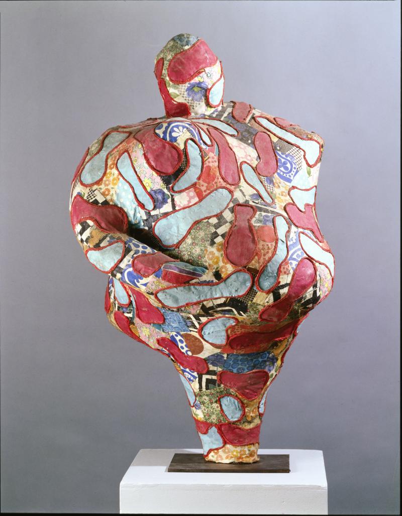 Abstrakte Skulptur in lebhaften Farben, mit geschwungenen Formen und Mustern, auf einem weißen Sockel präsentiert.