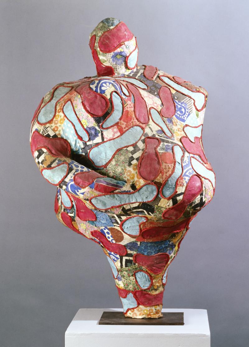 Skulptur mit organischen Formen, bunt marmoriert in Rot, Blau und verschiedenen Mustern, auf einem weißen Sockel.
