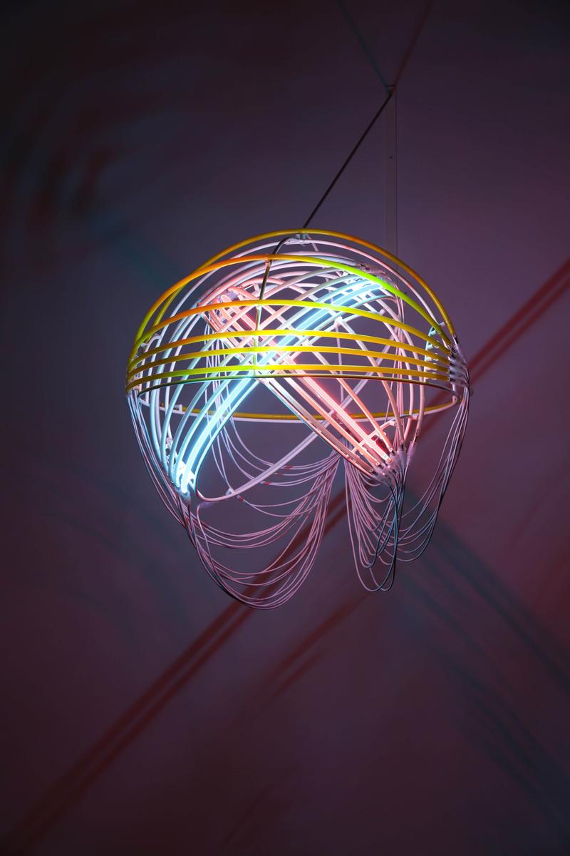 Hängende Lampe aus bunten Neonröhren, die ein filigranes, spiralförmiges Design bildet.