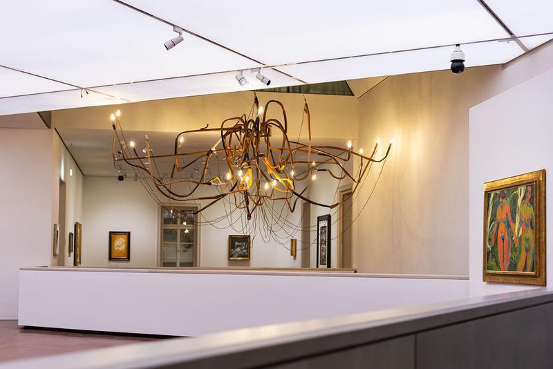 Moderne Galerie mit kunstvollem Kronleuchter und mehreren Gemälden an den Wänden.