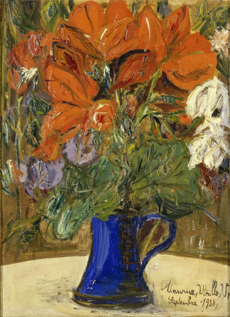 Bunter Blumenstrauß mit roten und weißen Blüten in einer blauen Kanne auf einem hellen Tisch.