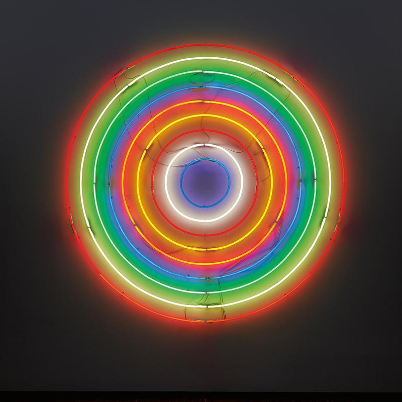 Bunte Neonröhren in konzentrischen Kreisen auf dunklem Hintergrund, die ein Zielmotiv darstellen.