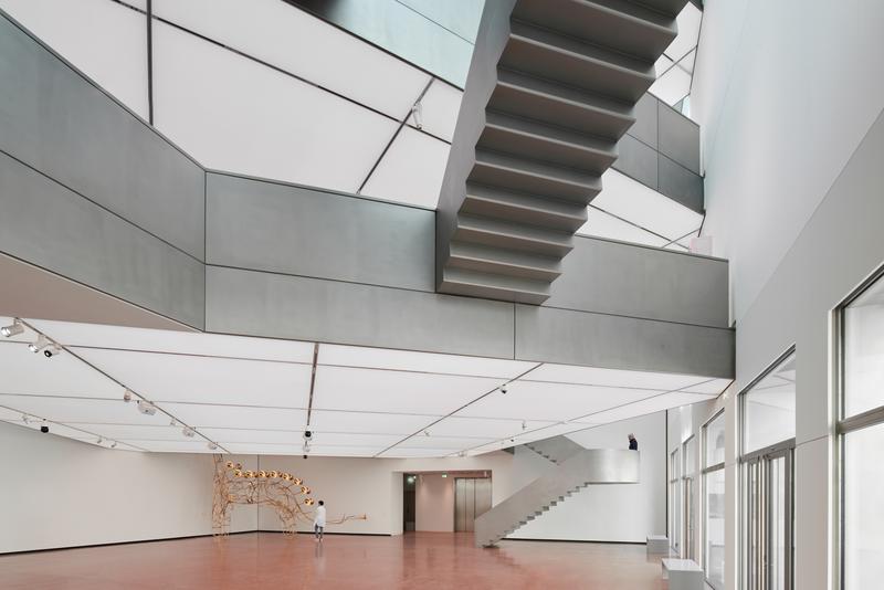 Helle, moderne Innenarchitektur mit geschwungener Treppe und kunstvollem Element aus Holz.