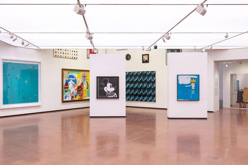 Moderne Galerie mit bunten Kunstwerken, weißen Wänden und einem glänzenden Boden.