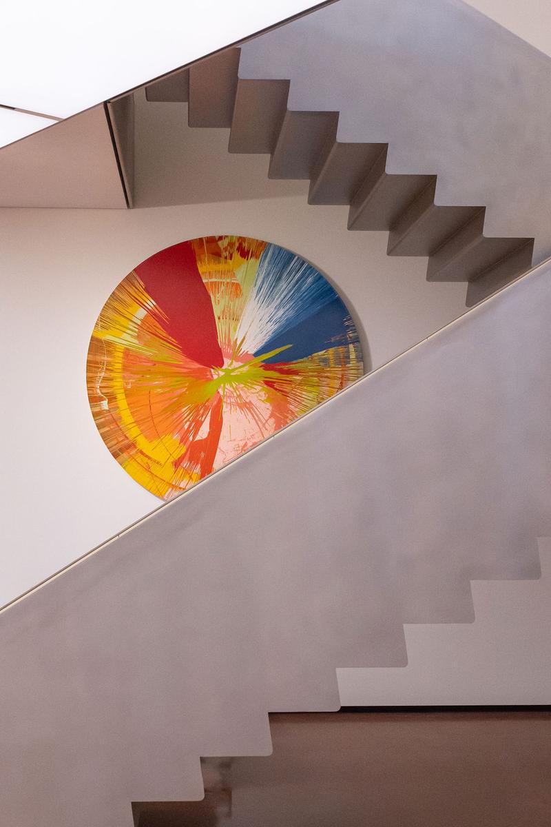 Blick auf eine moderne Treppe mit einem bunten, runden Kunstwerk an der Wand.