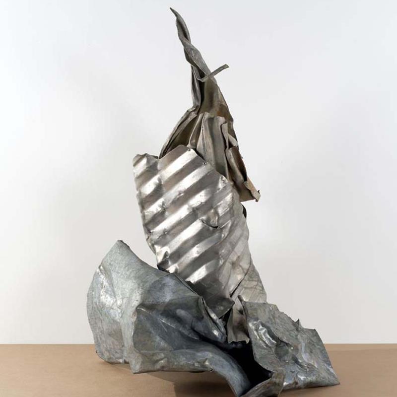 Abstrakte Skulptur aus gewelltem und glattem Metall, in silbernen Tönen, mit dynamischen Formen und Texturen.