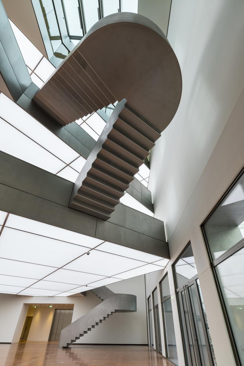 Schwebende Treppe in modernem Innenraum mit großen Fenstern und hellem Licht.