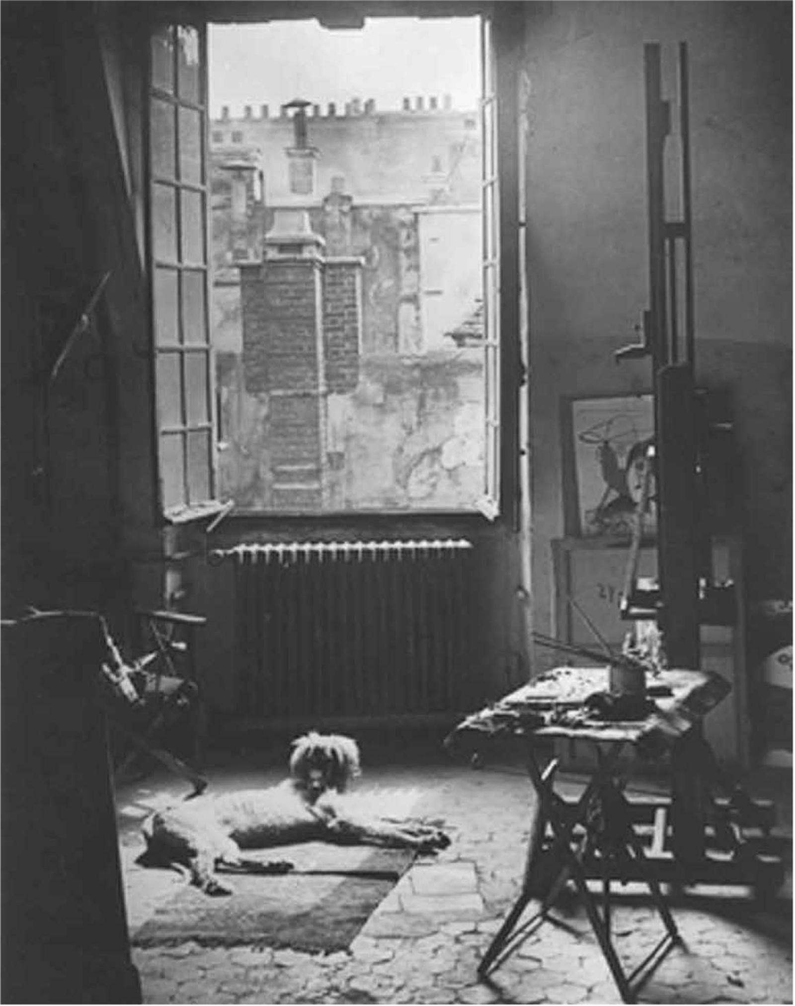 Heller Raum mit offenem Fenster, einem Hund auf dem Boden und Malutensilien auf einem Tisch.