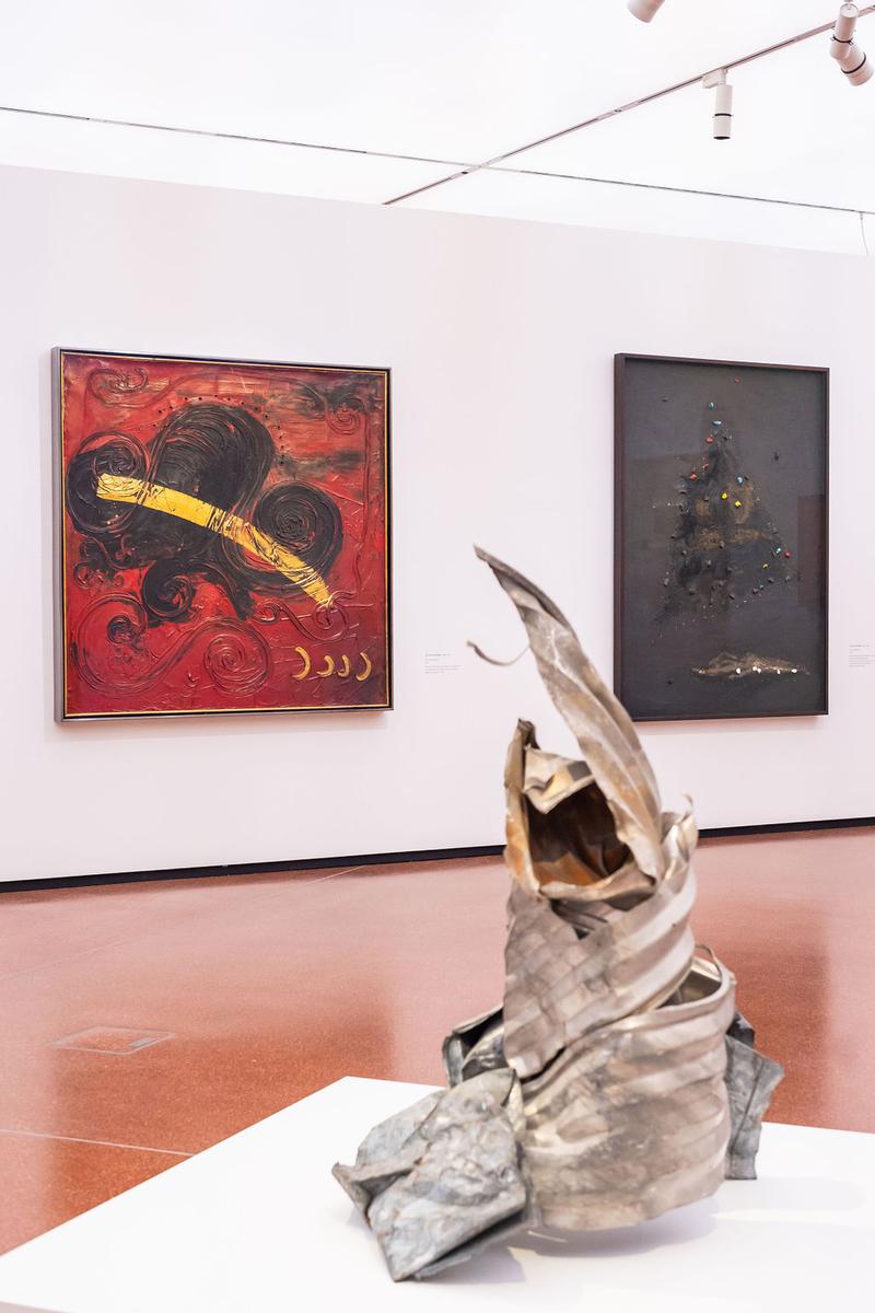 Abstrakte Malerei in Rot und Schwarz, daneben eine moderne Skulptur aus Metall in geschwungener Form.